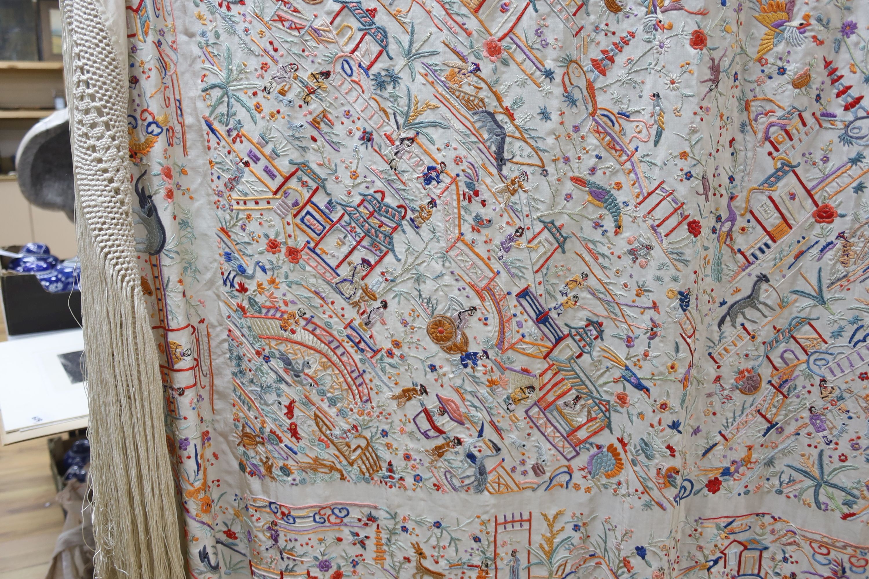 A Chinese cream silk shawl with fine multi coloured all over embroidery depicting figurative scenes and animals